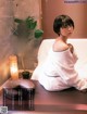 A woman in a bathrobe sitting on a bed.