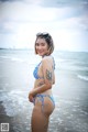 A woman in a blue bikini standing on the beach.