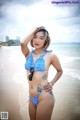 A woman in a blue bikini standing on a beach.