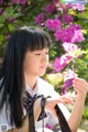 A woman in a school uniform holding a flower.