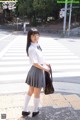 A woman in a school uniform is standing on the street.