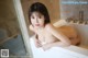 A naked asian woman sitting in a bathtub in a bathroom.