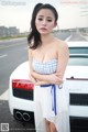 A woman in a white dress standing next to a white car.