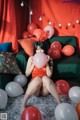 A woman sitting on a couch holding a bunch of balloons.