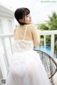 A woman in a white dress sitting on a chair.