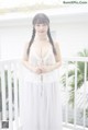 A woman in a white dress standing on a balcony.