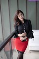 A woman in a black shirt and red skirt posing for a picture.