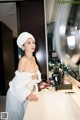 A woman in a white robe standing in front of a mirror.