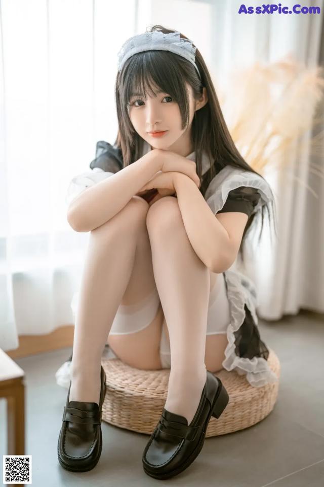 A woman sitting on top of a wicker basket wearing black shoes.