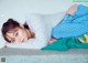 A young woman laying on top of a bed covered in blankets.