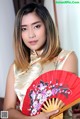 A woman in a chinese dress holding a red fan.