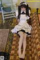 A woman in a maid outfit is sitting on a couch.