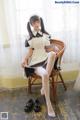 A woman sitting on a chair wearing a maid outfit.