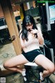 A woman sitting on a stool in front of a coffee machine.